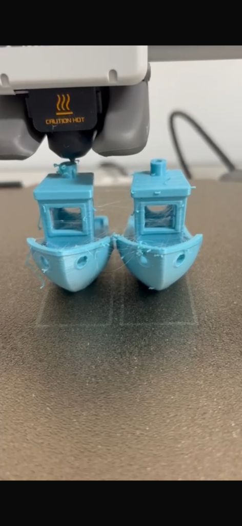 Dois barquinhos impressos em 3D em filamento azul, recém-saídos da minha impressora A1 mini.